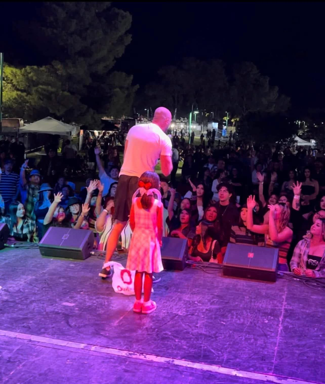 Jerry speaking to an outdoor audience with his daughter beside him onstage